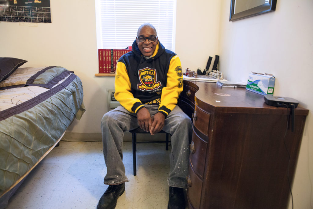 A man sitting on a chair in his bedroom at the West 140th Street residence.