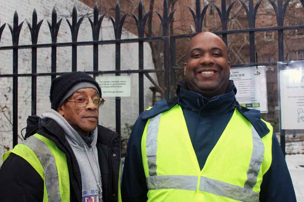 Two Green Keepers standing together smiling.
