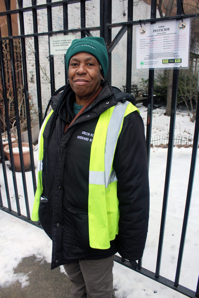 A Green Keeper standing by a garden smiling.