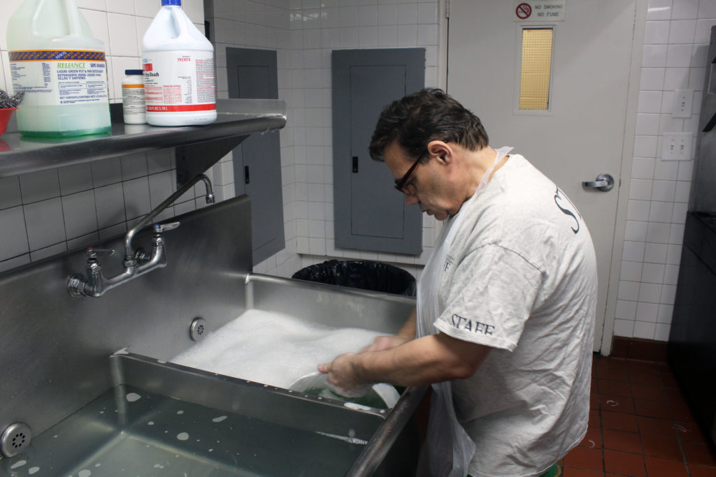 A TOPOP member washes dishes in a professional kitchen