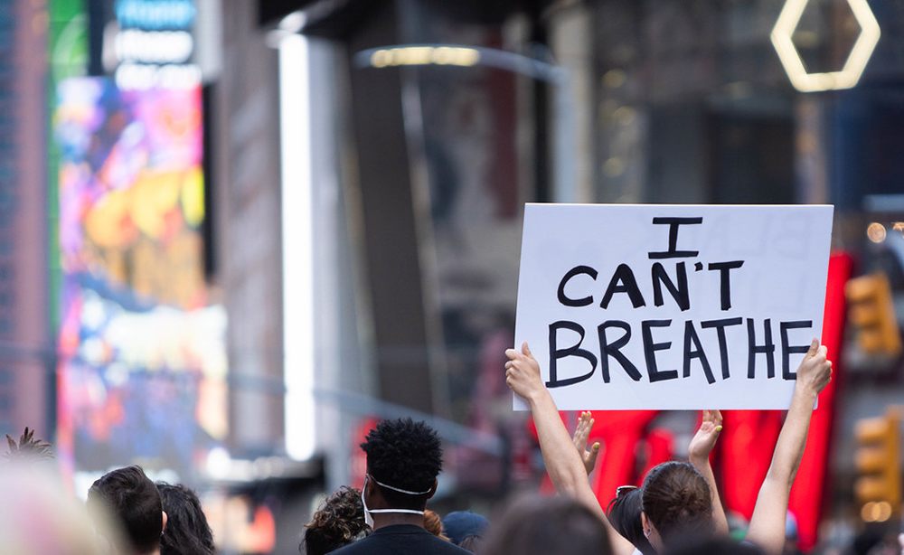 A protester in Times Square holds a sign saying "I Can't Breathe"