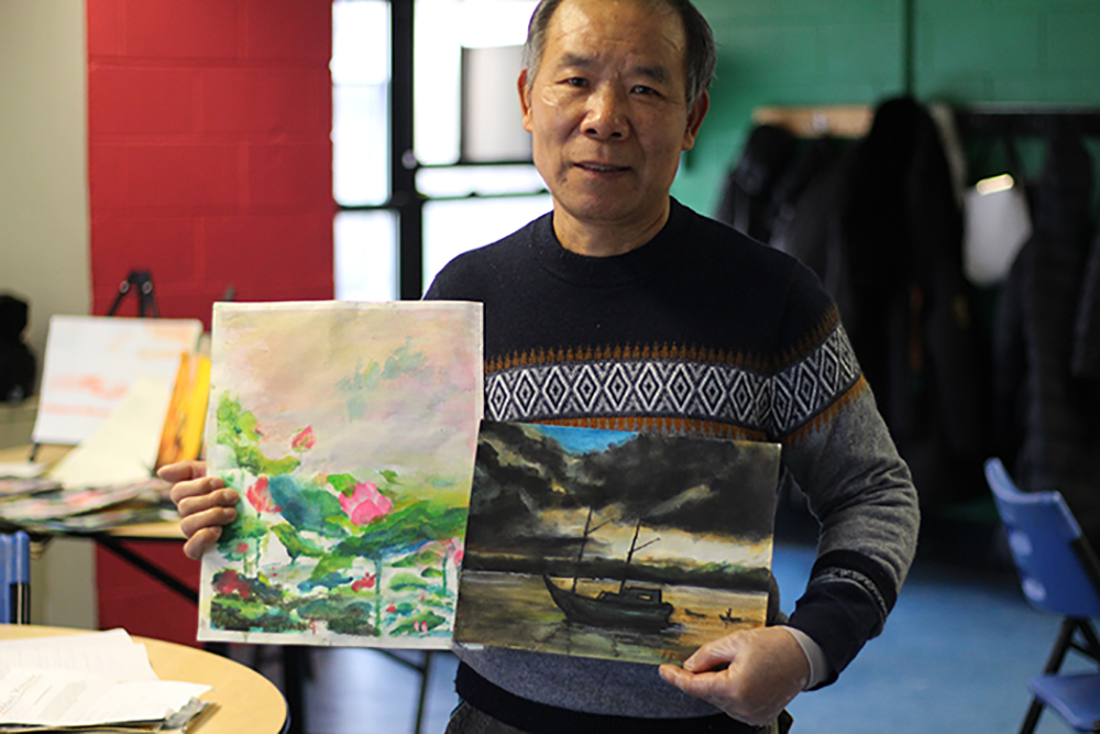 A man holding his painting from senior art classes