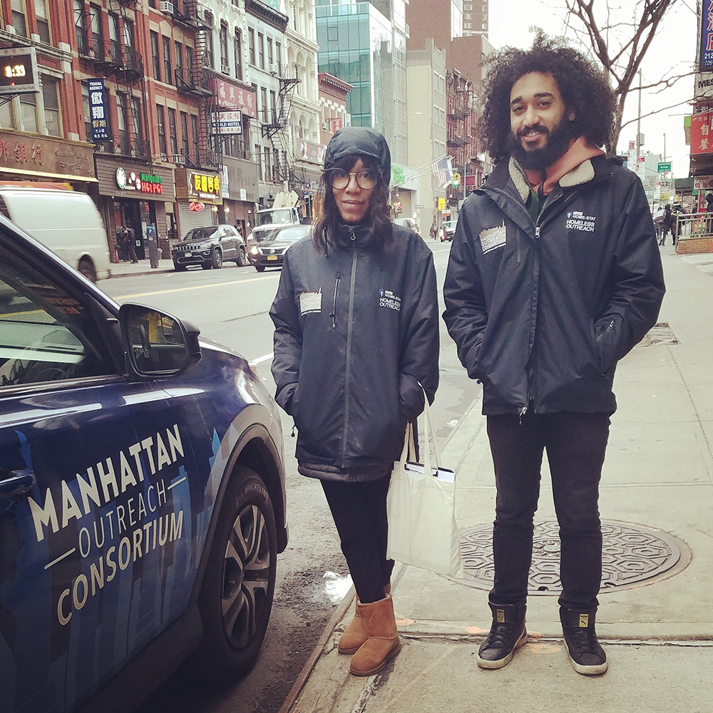Two homeless outreach specialists stand next to a Manhattan Outreach Consortium vehicle.