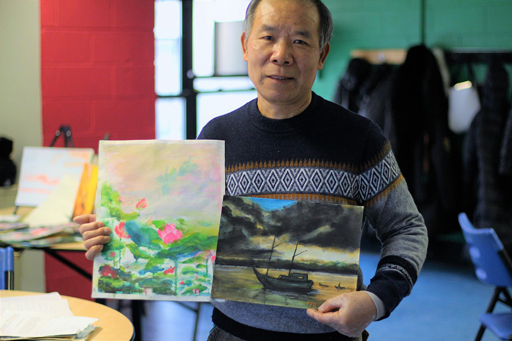 Huan Xin Huang poses with two of his watercolors