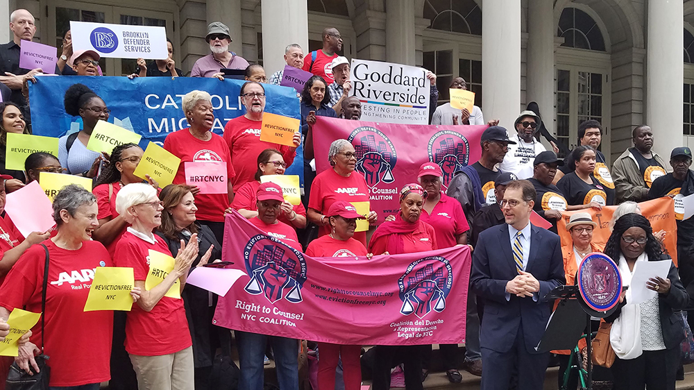 Activists crowd the NYC City Hall steps holding a variety of banners including Goddard Riverside's