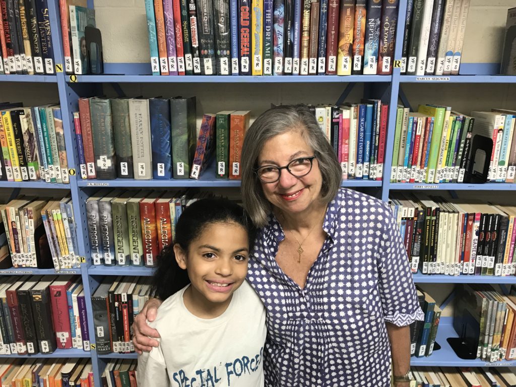 Crismary Lopez and her tutor Jane O’Connor stand in front of bookshelves at Star Learning Center
