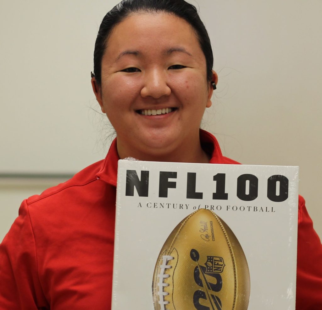 A woman holding a copy of the NFL 100 coffee table book