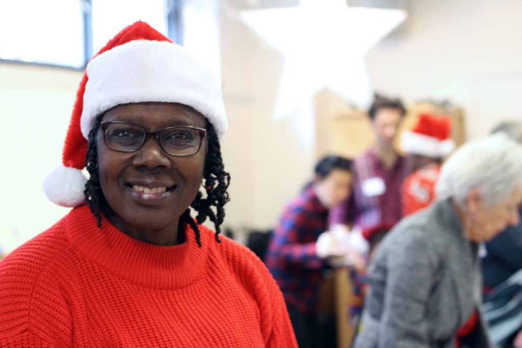A woman smiling wearing a Christmas hat