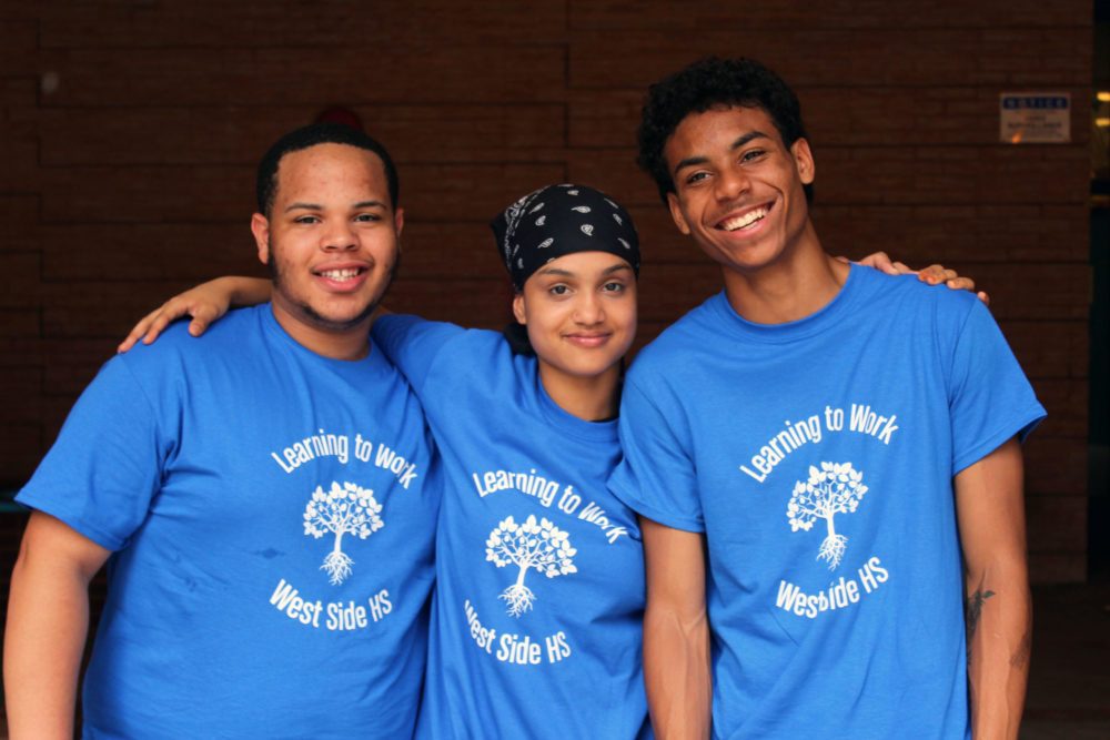 Three high school students standing together smiling