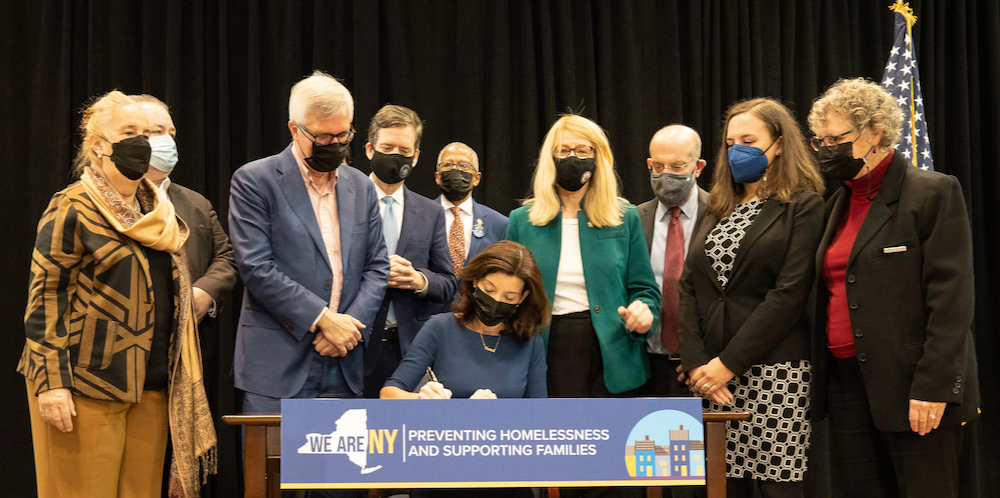 Lawmakers and advocates, including Goddard Riverside Deputy Executive Director Susan Matloff-Nieves, look on as Governor Kathy Hochul signs the bill (Photo: Office of the Governor) 