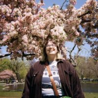 Tiffany Coelho standing in front of a flowering tree