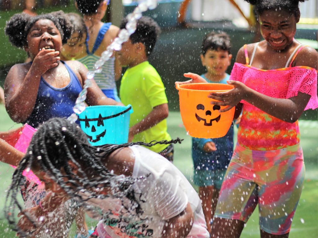 Kids playing in water with Halloween buckets. 