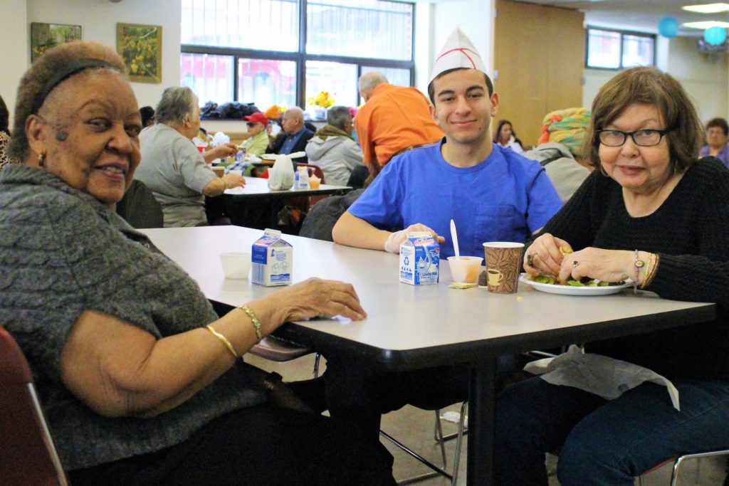 Trinity Changemaker Steven Schmidt shares a table with friends at Goddard Riverside's Columbus Avenue senior center. 