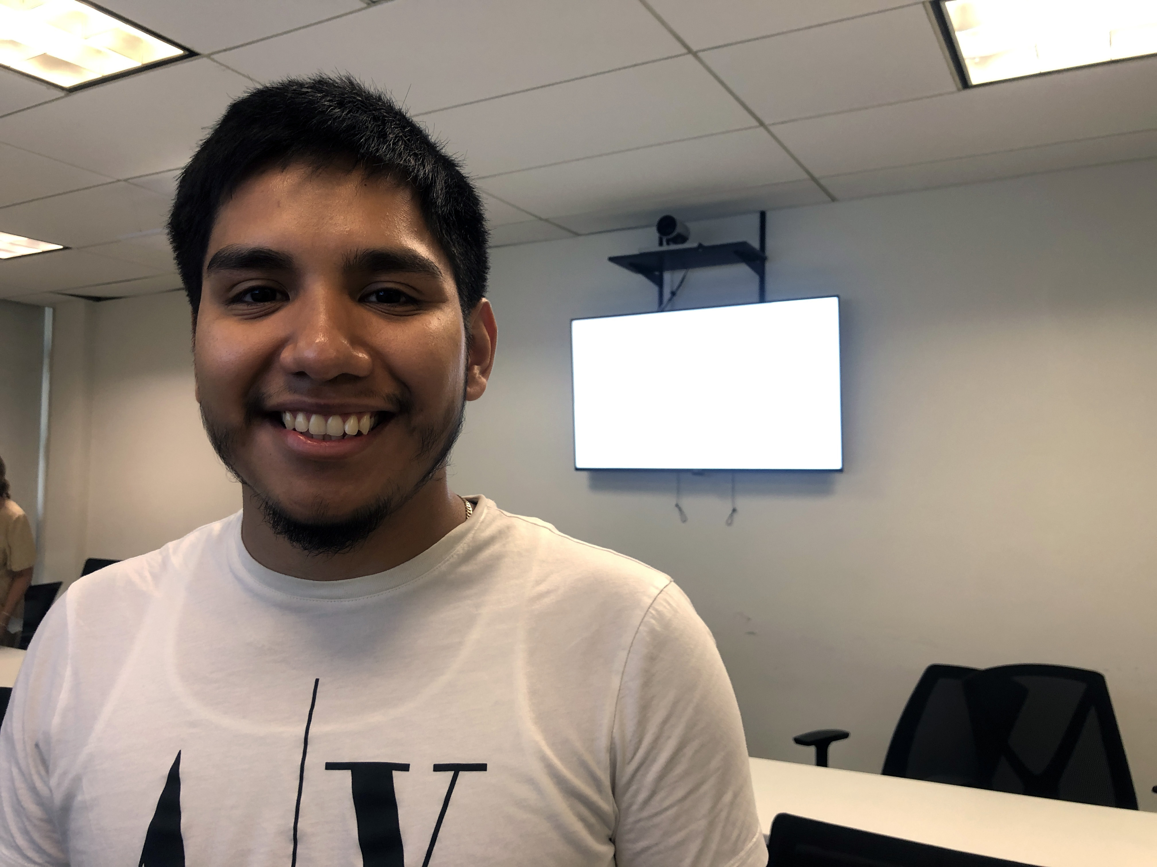 A young man smiling standing in a tech classroom