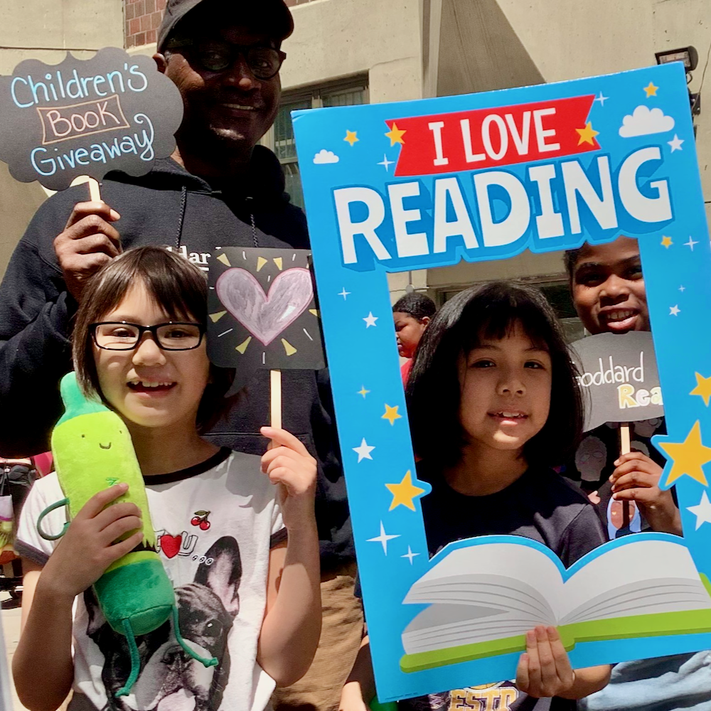 An adult and several children pose with an I Love Reading sign