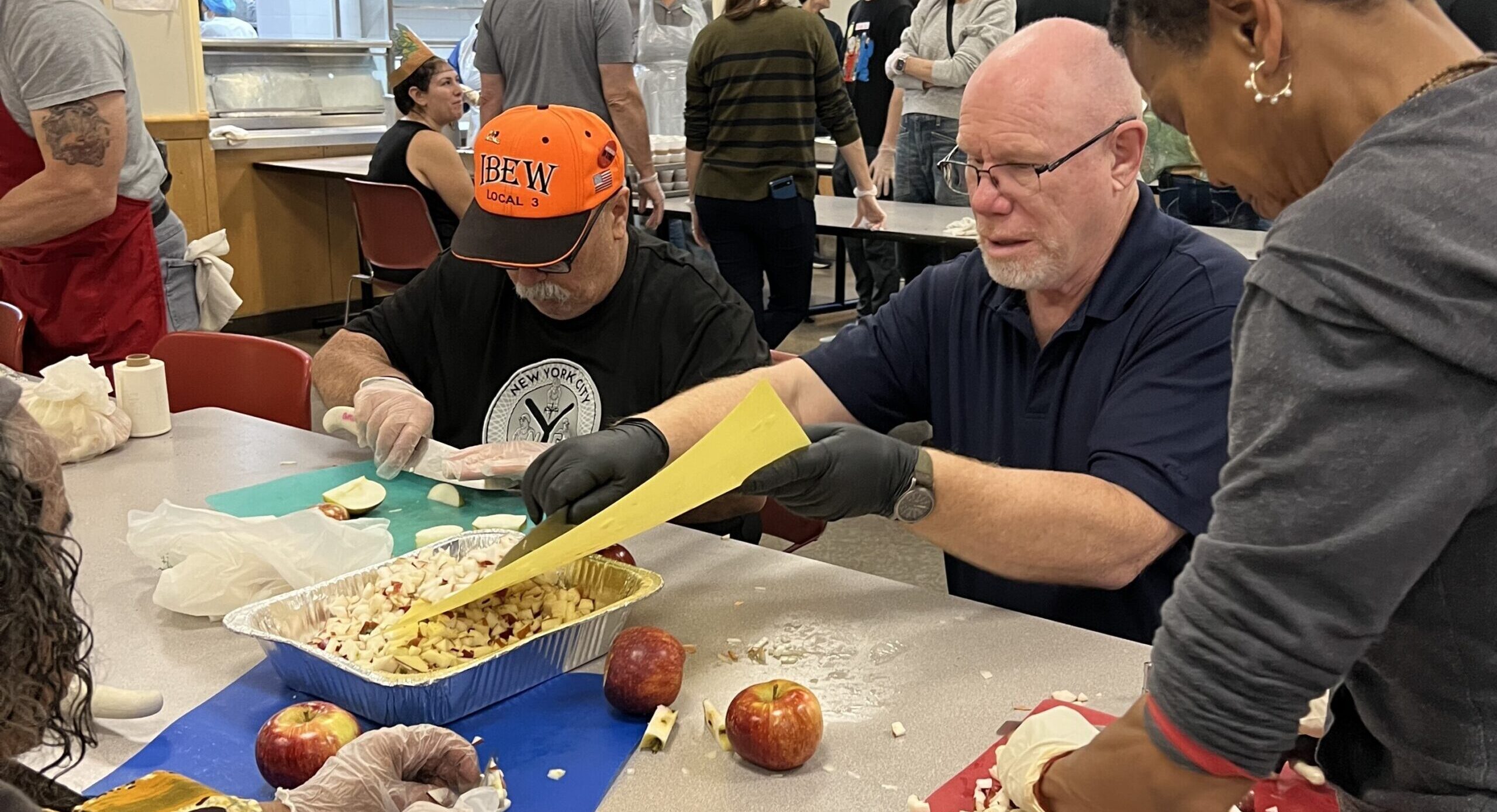 Volunteers chop apples at a long table