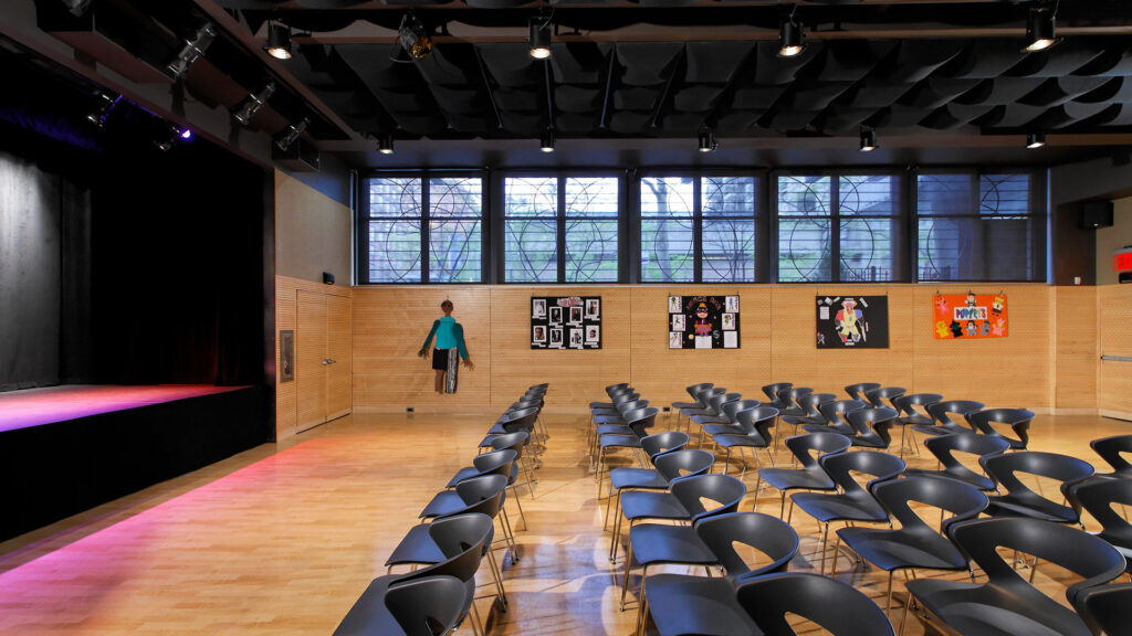 Auditorium with open floor space. Set up with chairs in front of a stage.