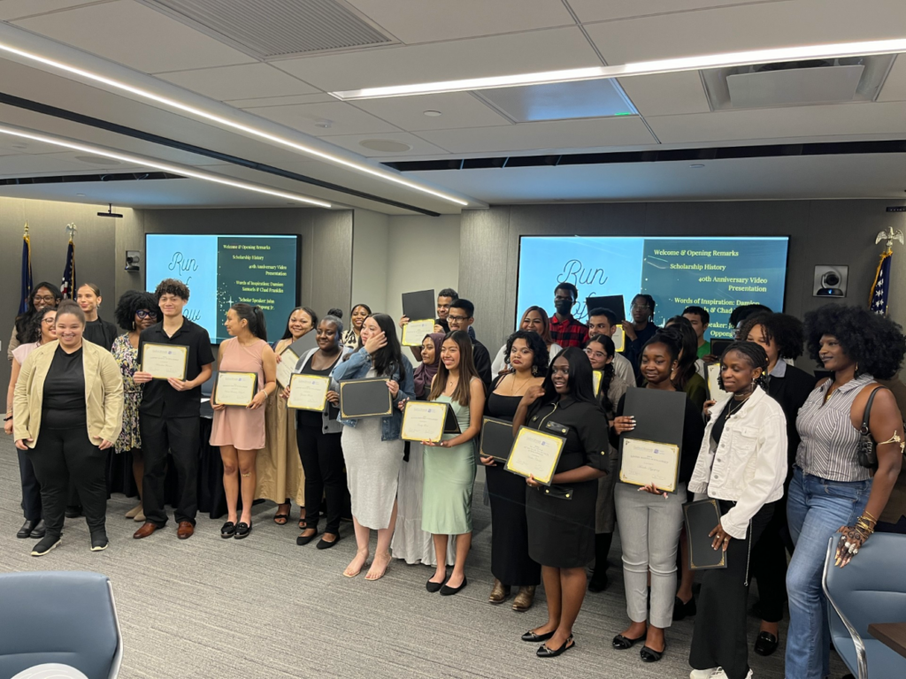 Some 30 young people stand holding their scholarship certificates along with Goddard and Isaacs Center staff