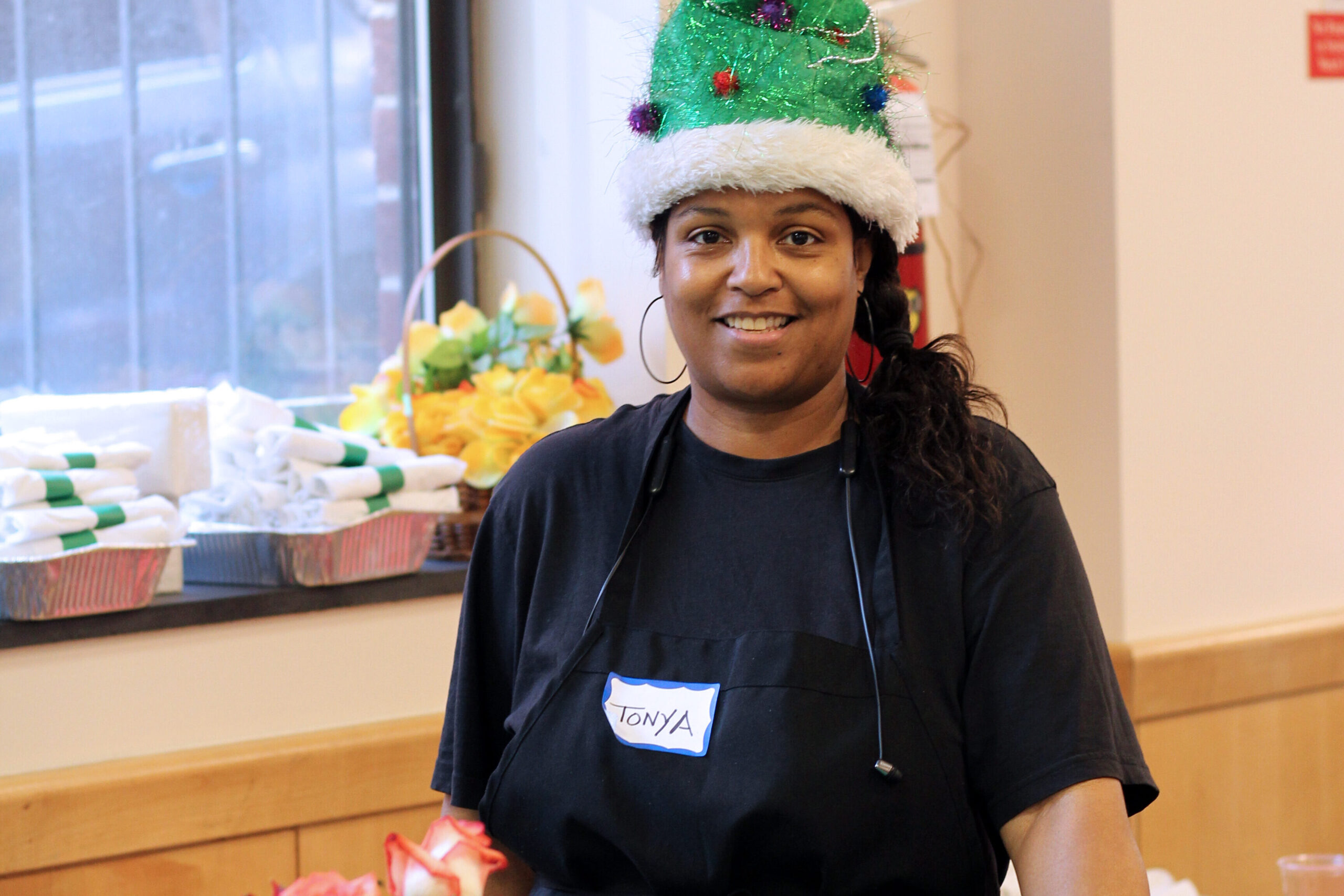 A woman standing by a table wearing a christmas hat.