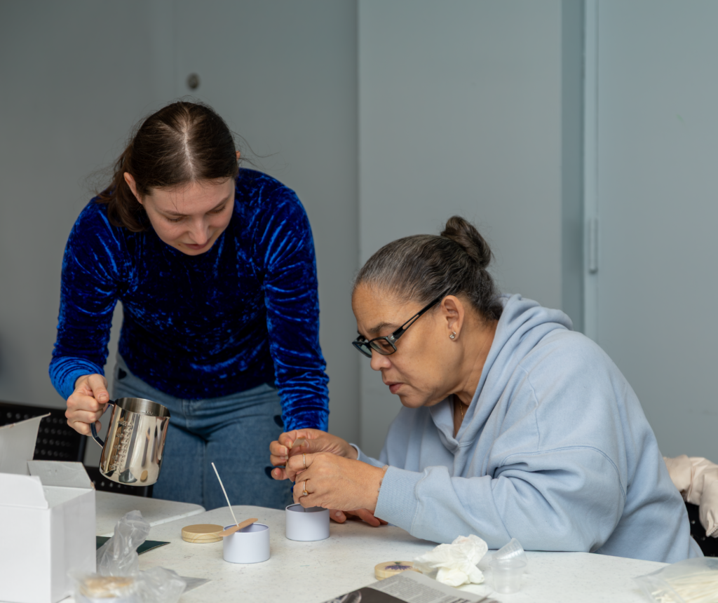 Candle making instructor helping and older adult during a workshop