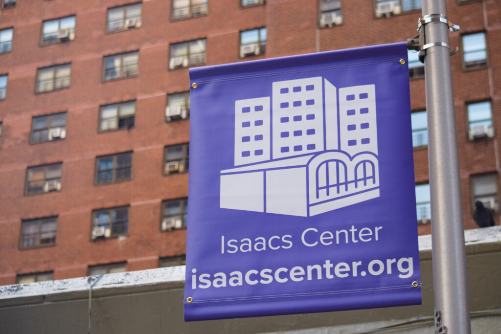 A banner with the Isaacs Center logo with one of the Isaacs and Holmes Towers in the background